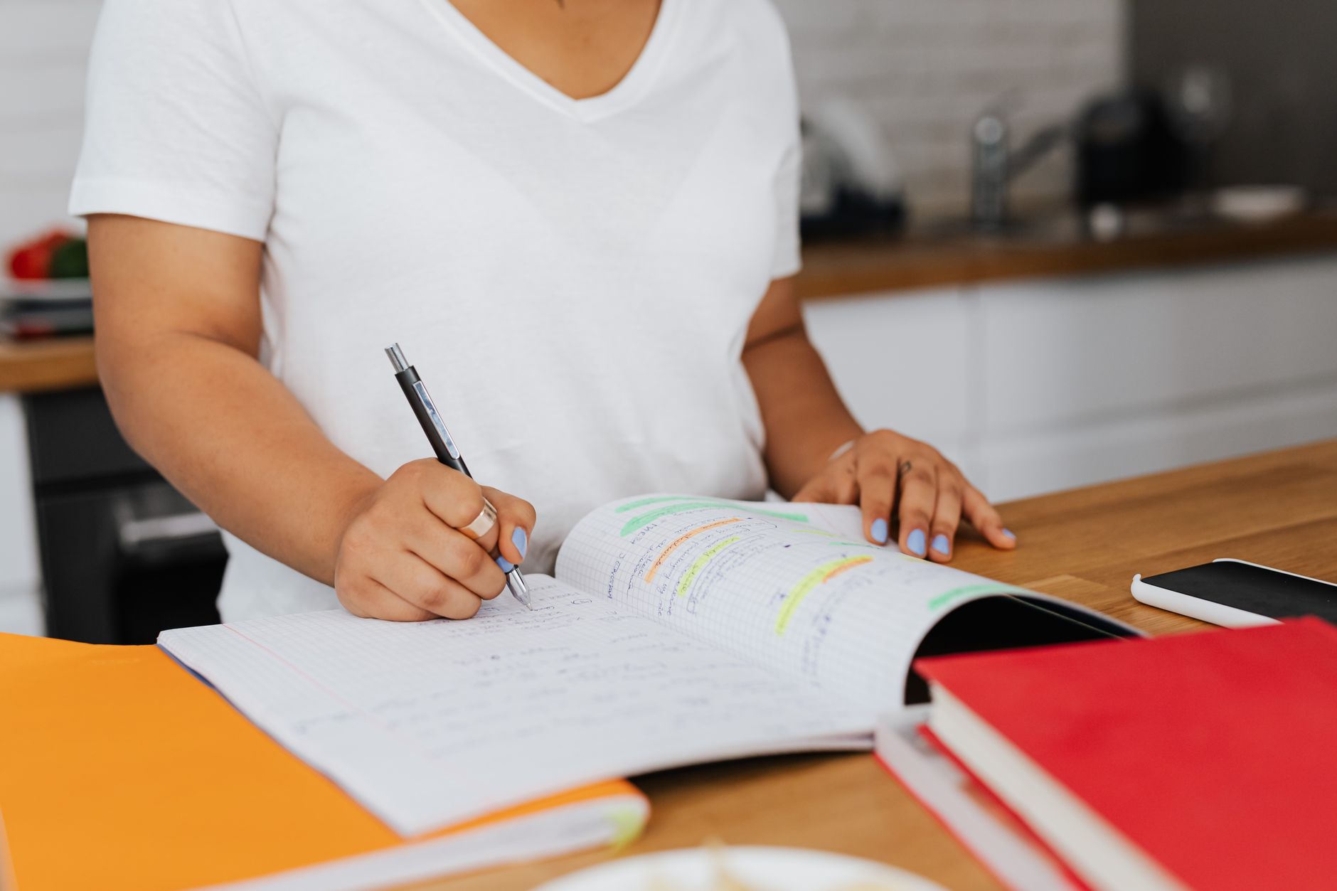 Woman writing a list in a notebook at her kitchen table
