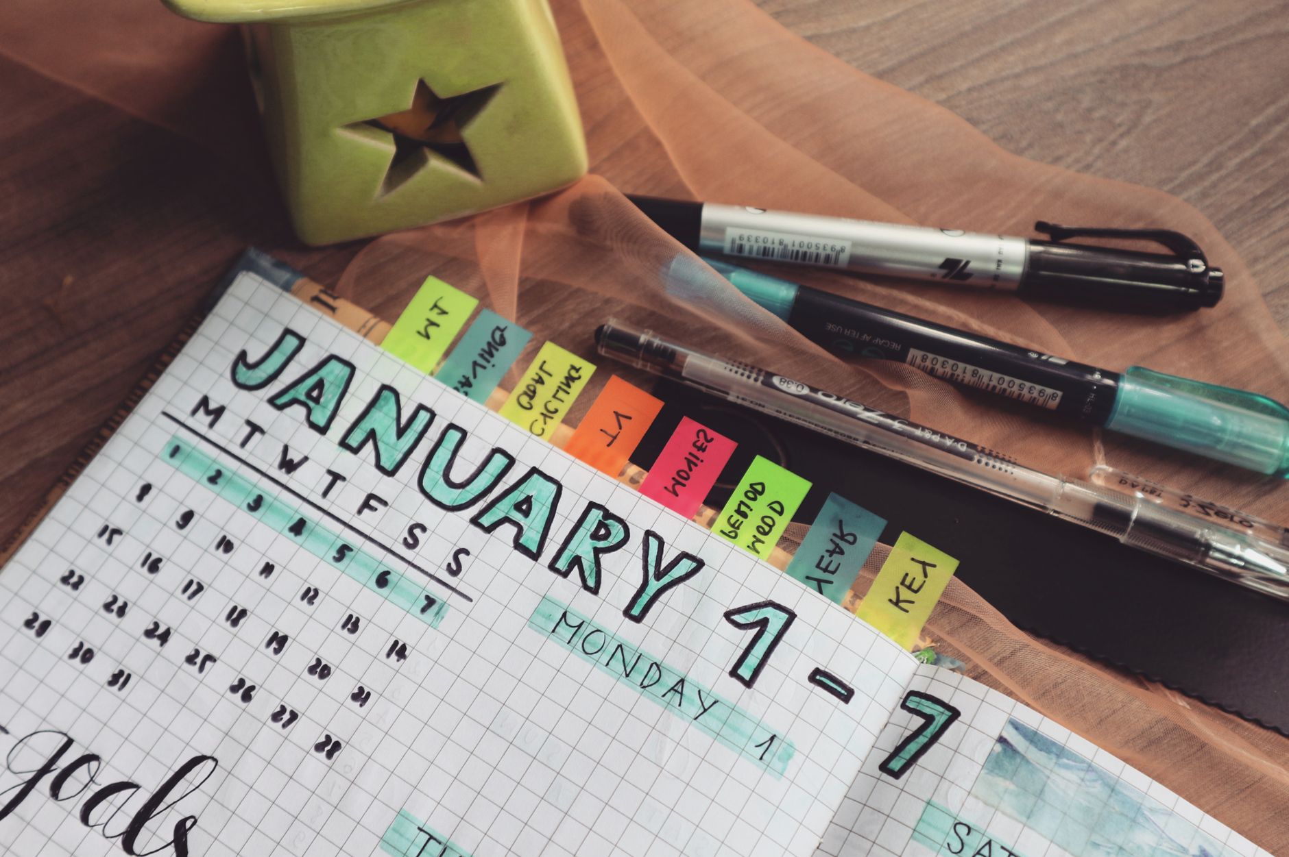 Planner with colorful tabs and pens on a wooden desk