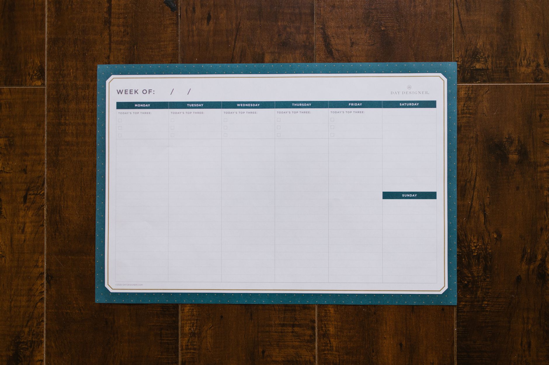 Blank weekly planner open on a wooden desk
